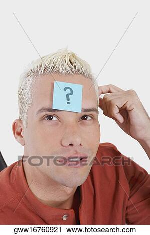 Stock Image - Close-up of a young man with an adhesive note on his forehead. Fotosearch