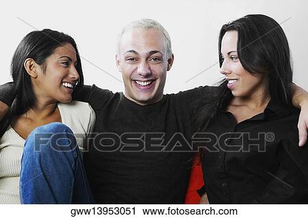 Close-up of a young man with his arm around two young women View Large Photo Image Stock Image - Close-up of a young man with his arm around two young women. Fotosearch