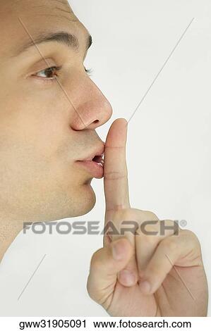 Close-up of a young man with his finger on his lips View Large Photo Image Stock Image - Close-up of a young man with his finger on his lips. Fotosearch