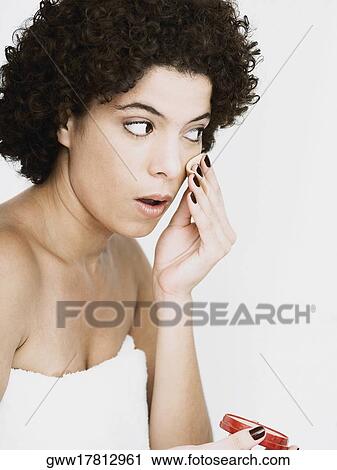 Close-up of a young woman applying face powder on her face View Large Photo Image Stock Image - Close-up of a young woman applying face powder on her face. Fotosearch