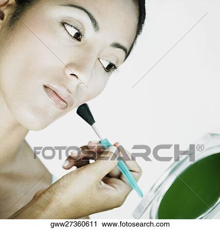 Stock Image - Close-up of a young woman applying make-up with a make-up brush. Fotosearch