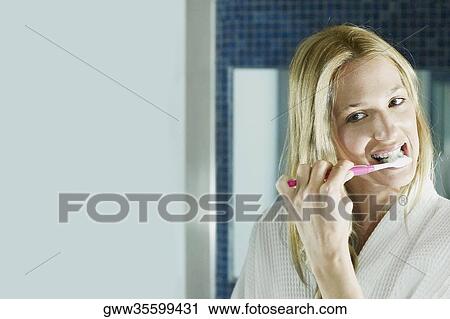 Stock Image - Close-up of a young woman brushing her teeth. Fotosearch