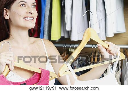 Close-up of a young woman choosing tops in a clothing store View Large Photo Image Stock Image - Close-up of a young woman choosing tops in a clothing store. Fotosearch