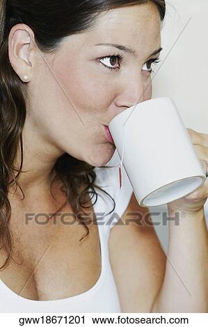 Close-up of a young woman drinking a cup of tea View Large Photo Image Stock Image - Close-up of a young woman drinking a cup of tea. Fotosearch