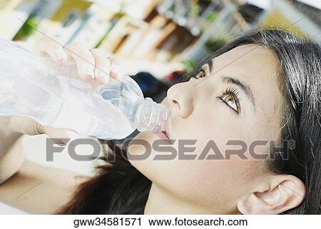 Close-up of a young woman drinking water from a bottle View Large Photo Image Stock Image - Close-up of a young woman drinking water from a bottle. Fotosearch