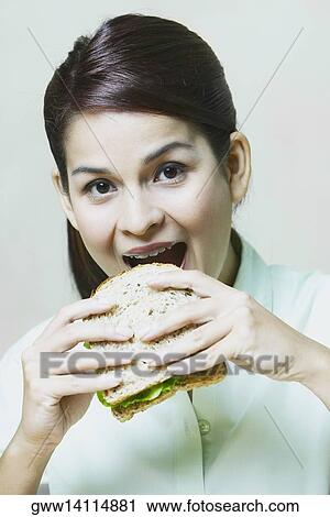 Close-up of a young woman eating a sandwich View Large Photo Image Stock Image - Close-up of a young woman eating a sandwich. Fotosearch