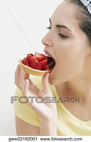 Close-up of a young woman eating a strawberry tart View Large Photo Image Stock Image - Close-up of a young woman eating a strawberry tart. Fotosearch