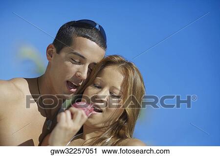 Close-up of a young woman eating an ice-cream with a mid adult man beside her View Large Photo Image Stock Image - Close-up of a young woman eating an ice-cream with a mid adult man beside her. Fotosearch