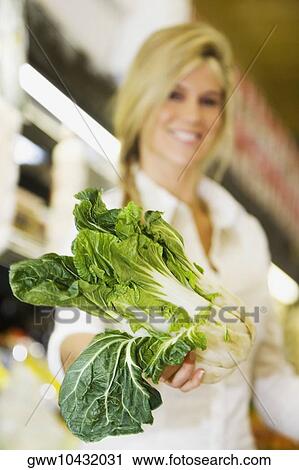 Close-up of a young woman holding a bok choy in a supermarket View Large Photo Image Stock Image - Close-up of a young woman holding a bok choy in a supermarket. Fotosearch