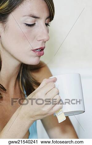 Stock Image - Close-up of a young woman holding a cup of tea. Fotosearch