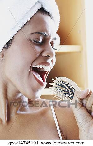 Close-up of a young woman holding a hairbrush and singing View Large Photo Image Stock Image - Close-up of a young woman holding a hairbrush and singing. Fotosearch