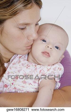Close-up of a young woman kissing her baby girl View Large Photo Image Stock Image - Close-up of a young woman kissing her baby girl. Fotosearch