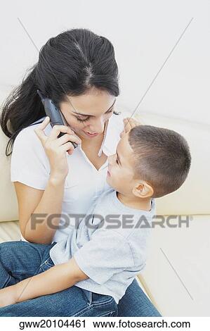 Close-up of a young woman on the phone and her son sitting on her lap View Large Photo Image Stock Image - Close-up of a young woman on the phone and her son sitting on her lap. Fotosearch