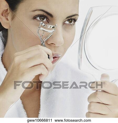 Close-up of a young woman using a eyelash curler View Large Photo Image Stock Image - Close-up of a young woman using a eyelash curler. Fotosearch