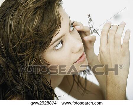Close-up of a young woman using an eyelash curler View Large Photo Image Stock Image - Close-up of a young woman using an eyelash curler. Fotosearch
