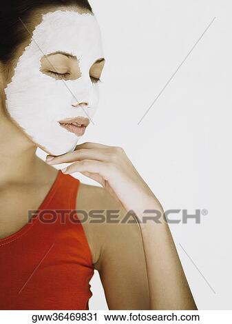 Stock Image - Close-up of a young woman wearing a facial mask with her eyes closed . Fotosearch