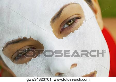 Stock Image - Close-up of a young woman with a facial mask on her face. Fotosearch
