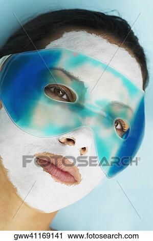 Stock Image - Close-up of a young woman with a facial mask and an eye mask on her face. Fotosearch