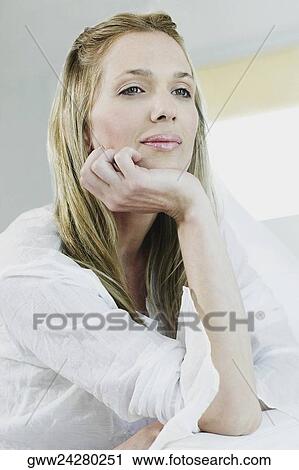 Stock Image - Close-up of a young woman with her hand on her chin. Fotosearch
