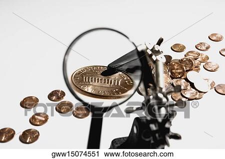 Stock Image - Close-up of coins and a magnifying glass. Fotosearch