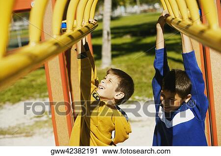 Stock Image - Close-up of two brothers hanging on a jungle gym. Fotosearch