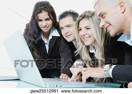 Stock Image - Close-up of two businessmen and two businesswomen using a laptop. Fotosearch