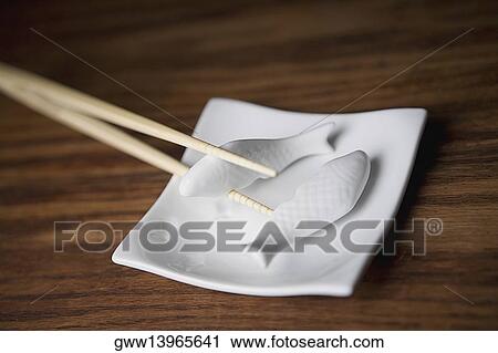 Close-up of two chopsticks holding the figurine of a fish View Large Photo Image Stock Image - Close-up of two chopsticks holding the figurine of a fish. Fotosearch