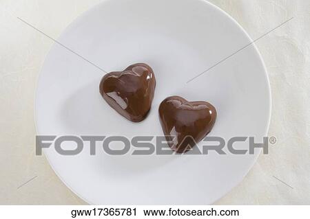 Close-up of two heart shaped chocolate candies in a plate View Large Photo Image Stock Image - Close-up of two heart shaped chocolate candies in a plate. Fotosearch