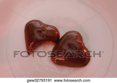 Stock Image - Close-up of two heart shaped chocolate candies in a plate. Fotosearch