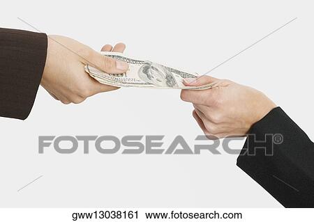 Stock Image - Close-up of two people's hands holding American paper currency. Fotosearch