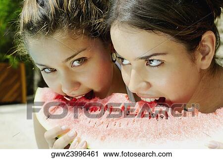 Close-up of two young women eating a slice of watermelon View Large Photo Image Stock Image - Close-up of two young women eating a slice of watermelon. Fotosearch