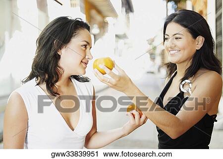 Close-up of two young women holding oranges and looking at each other View Large Photo Image Stock Image - Close-up of two young women holding oranges and looking at each other. Fotosearch