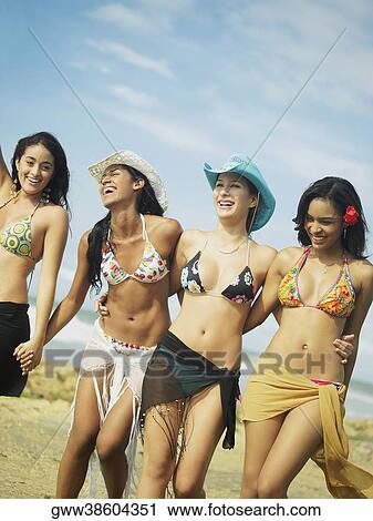 Four young women walking together on the beach View Large Photo Image Stock Image - Four young women walking together on the beach. Fotosearch