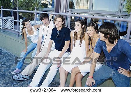 Stock Image - Group of friends sitting on a ledge. Fotosearch