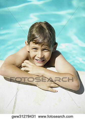 Stock Image - High angle view of a boy leaning at the edge of a swimming pool. Fotosearch