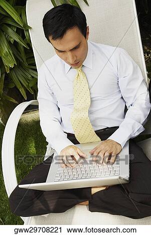 High angle view of a businessman using a laptop and sitting on a lounge chair View Large Photo Image Stock Image - High angle view of a businessman using a laptop and sitting on a lounge chair. Fotosearch