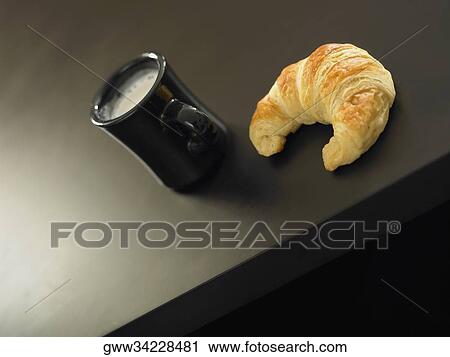 High angle view of a cup of coffee and a croissant on a table View Large Photo Image Stock Image - High angle view of a cup of coffee and a croissant on a table. Fotosearch