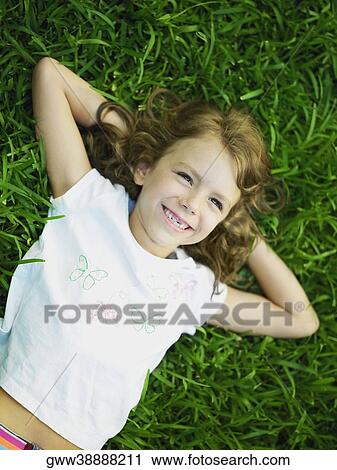 Stock Image - High angle view of a girl lying on the grass. Fotosearch