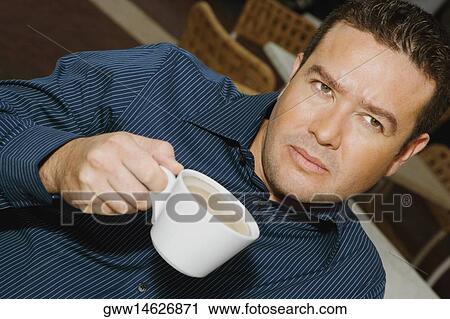 Stock Image - High angle view of a mid adult man drinking a cup of tea. Fotosearch