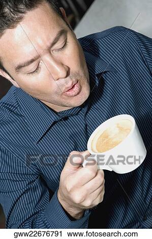 High angle view of a mid adult man blowing into a tea cup View Large Photo Image Stock Image - High angle view of a mid adult man blowing into a tea cup. Fotosearch