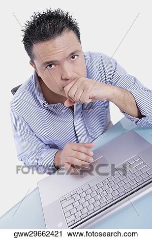 High angle view of a mid adult man sitting in front of a laptop View Large Photo Image Stock Image - High angle view of a mid adult man sitting in front of a laptop. Fotosearch