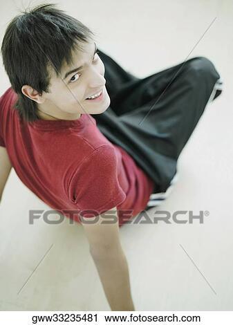 High angle view of a mid adult man sitting on the floor and smiling View Large Photo Image Stock Image - High angle view of a mid adult man sitting on the floor and smiling. Fotosearch