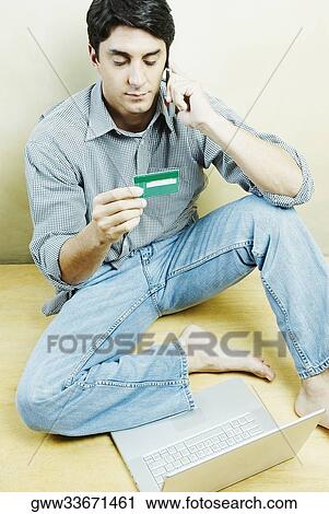 High angle view of a mid adult man talking on a mobile phone and holding a credit card View Large Photo Image Stock Image - High angle view of a mid adult man talking on a mobile phone and holding a credit card. Fotosearch