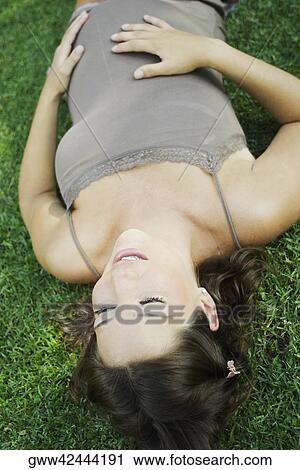 High angle view of a pregnant young woman lying on the grass and touching her abdomen View Large Photo Image Stock Image - High angle view of a pregnant young woman lying on the grass and touching her abdomen. Fotosearch