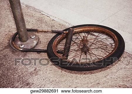 Stock Image - High angle view of a wheel locked to a pole. Fotosearch
