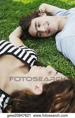 High angle view of a young couple lying on the grass in a park View Large Photo Image Stock Image - High angle view of a young couple lying on the grass in a park. Fotosearch