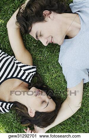 High angle view of a young couple lying on the grass in a park View Large Photo Image Stock Image - High angle view of a young couple lying on the grass in a park. Fotosearch