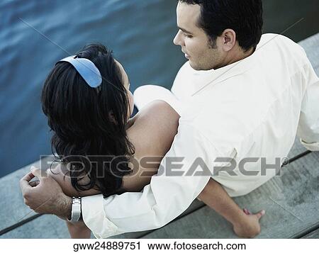 High angle view of a young couple sitting on a pier View Large Photo Image Stock Image - High angle view of a young couple sitting on a pier. Fotosearch