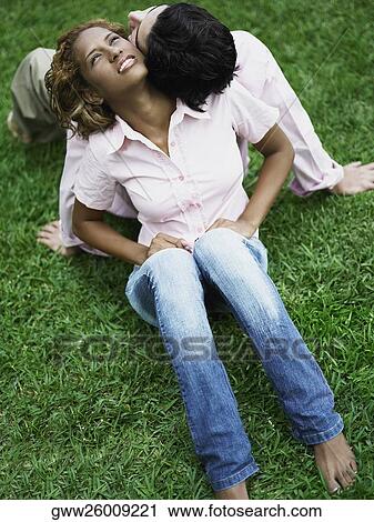 Stock Image - High angle view of a young couple sitting back to back. Fotosearch