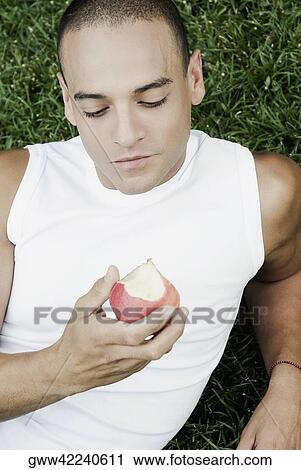 High angle view of a young man holding an apple View Large Photo Image Stock Image - High angle view of a young man holding an apple. Fotosearch